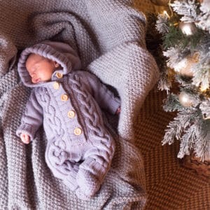 Baby boy sleeping under the Christmas tree on New Year's Eve
